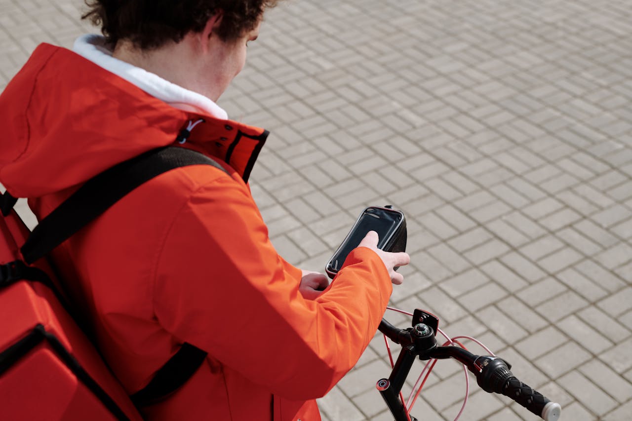 Delivery man on a bicycle checking smartphone for directions.